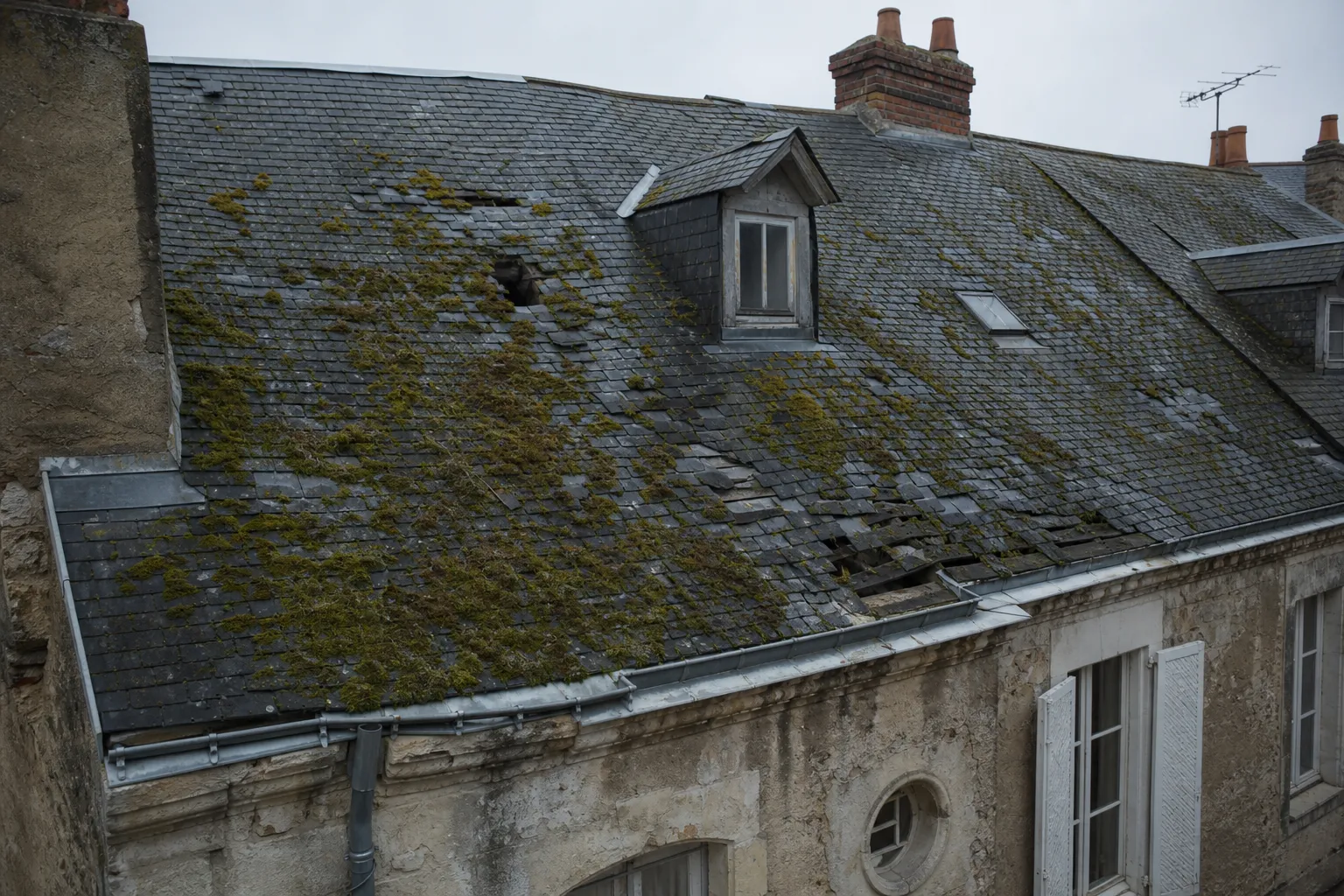 Toiture ancienne endommagée avant rénovation : ardoises cassées et mousse